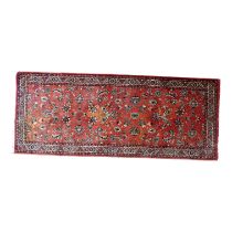 A small Persian runner - of floral design on a red ground, 196 x 80cm