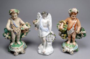 A 19th century German putto - holding a basket of flowers, height 13cm, together with another and