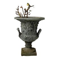 A lead garden urn of campana form - with twin handles and modelled with figures in low relief,