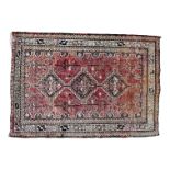Persian rug - with an arrangement of three medallions on a red ground within a serrated multi-stripe