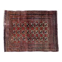 A Bokhara rug - decorated with an arrangement of gul motifs on a red ground, the border with