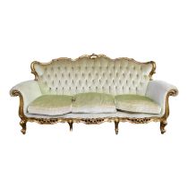 A Louis XV style button upholstered sofa - with a carved gilt frame and raised on short cabriole