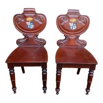 A pair of Victorian mahogany hall chairs - the shaped scroll backs painted with family armorials,