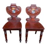 A pair of Victorian mahogany hall chairs - the shaped scroll backs painted with family armorials,