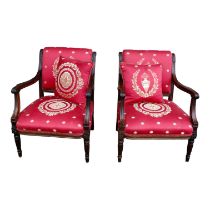 A pair of mahogany French Empire style chairs - with pad backs and open arms, on turned reeded legs.