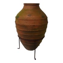 A terracotta olive oil storage jar - of ribbed barrel form and raised on a iron tripod frame, 73cm