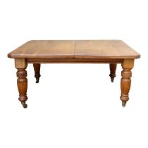 A late Victorian walnut dining table - the rectangular top with canted corners, on turned and reeded