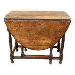 A 17th century style oak drop leaf table, the oval mounted top on square and turned legs joined by