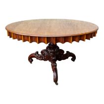 A circular mahogany dining table - the moulded top above a fluted frieze, on a leaf carved and