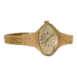 A ladies Longines 9ct gold watch - the oval dial set out with baton numerals, the textured case with