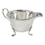 A silver cream jug - Birmingham 1921, with a foliate band to lip and raised on three pad feet,