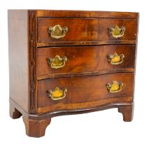 A George III style walnut miniature chest of drawers - of serpentine form with three drawers on