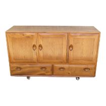 An Ercol elm sideboard - Windsor model 468, with an arrangement of three doors, each enclosing an