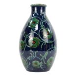 A majolica vase by Alfred Kusche - of baluster form and decorated with trailing foliage on a blue