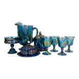 A collection of blue carnival glass - iridescent and moulded with grapes and vines, including a jug,