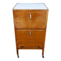 An early 20th century oak 'hospital' bedside cupboard - with a Formica top above two cupboards