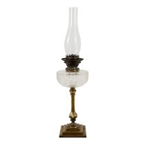 A late Victorian glass and brass oil lamp - with a cut glass reservoir raised on a column support