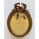 Oval mirror in gilt wood 'instruments'
