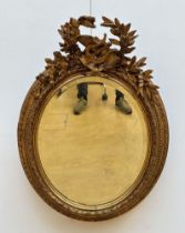 Oval mirror in gilt wood 'instruments'
