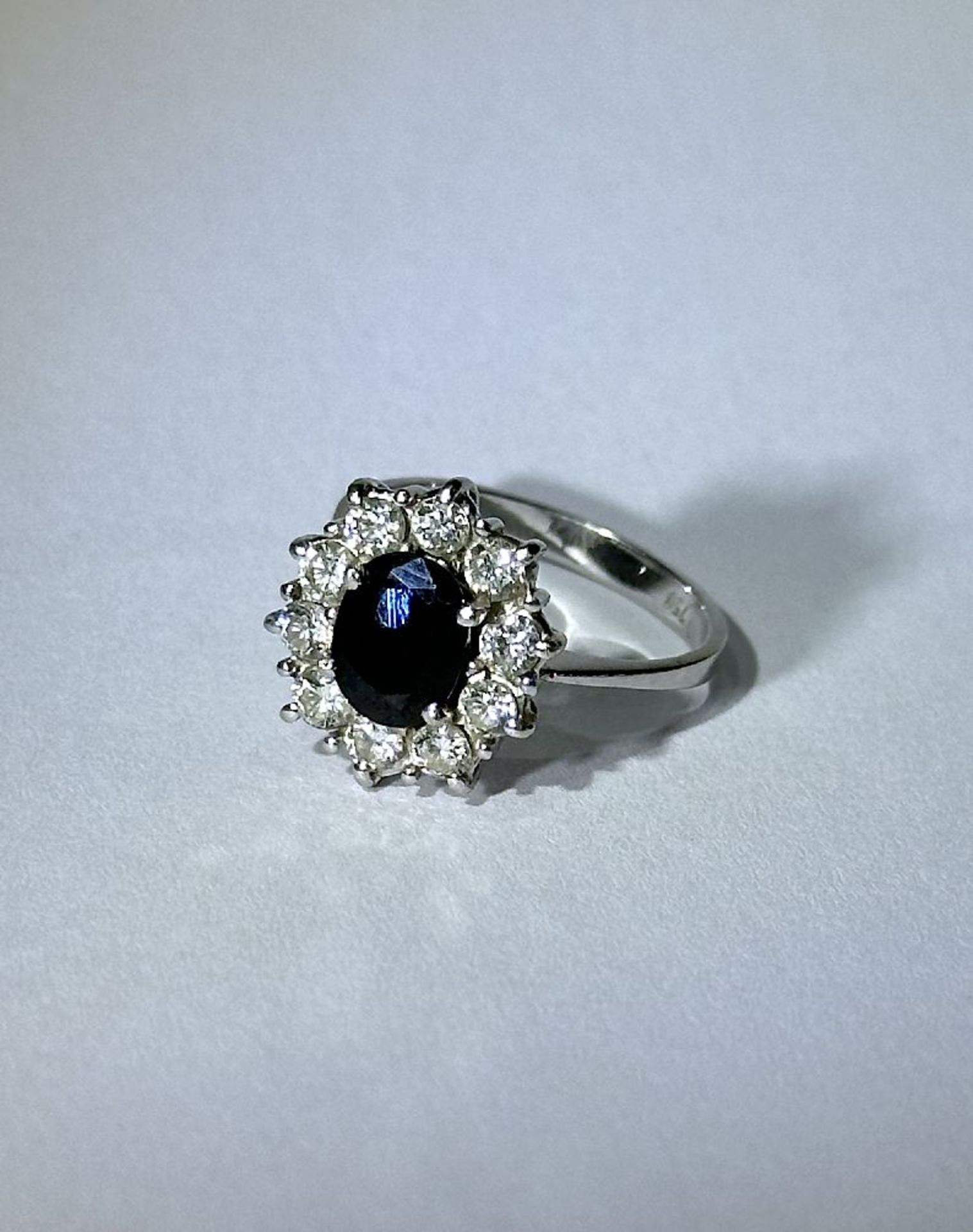 White gold women's ring with sapphire surrounded by diamonds