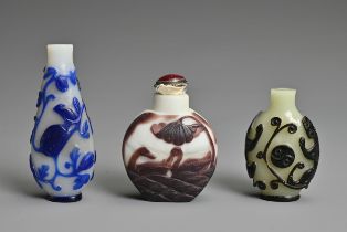 THREE CHINESE GLASS OVERLAY SNUFF BOTTLES. To include a black overlay bottle with chilong and yin