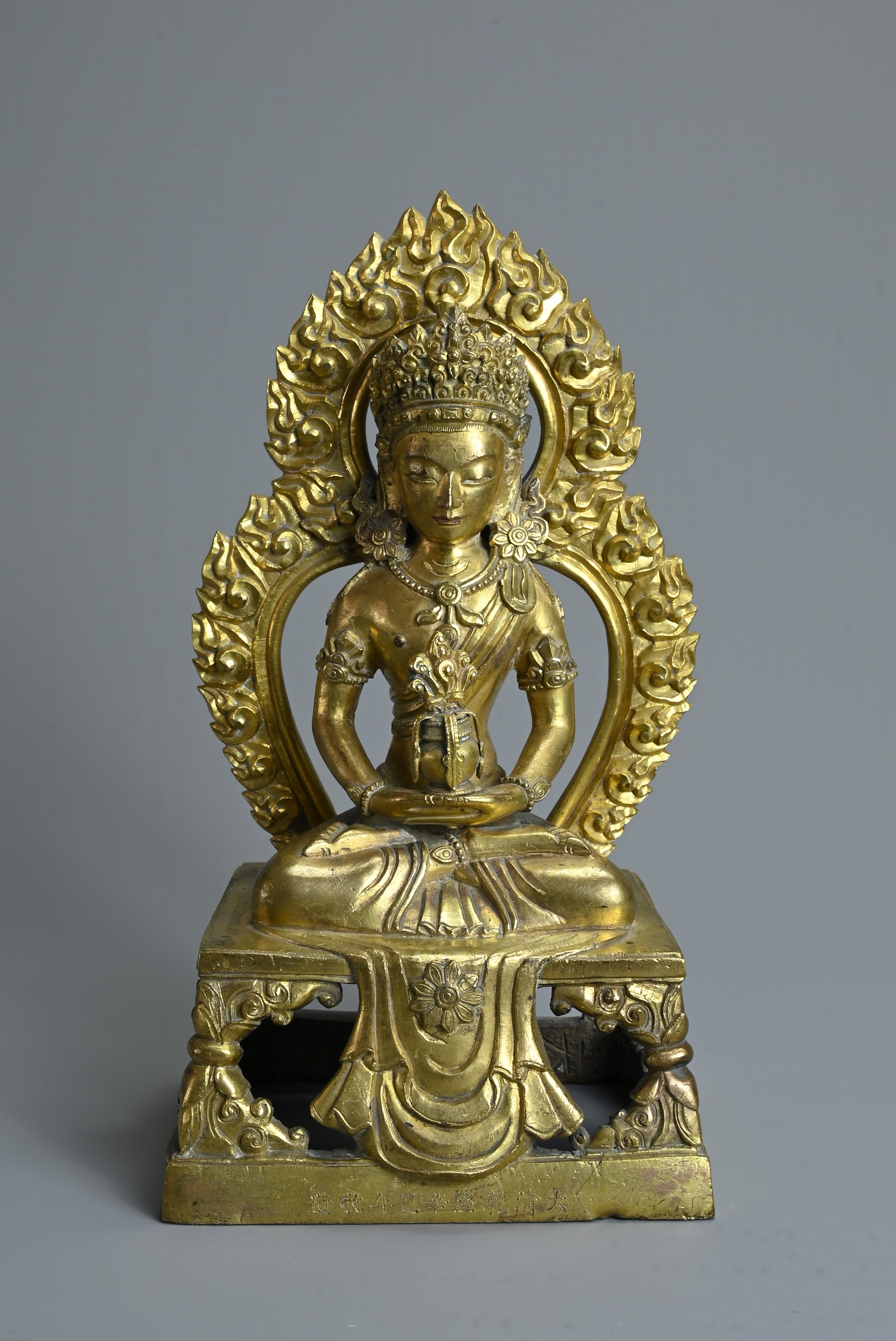 A CHINESE GILT BRONZE FIGURE OF AMITAYUS, QIANLONG PERIOD (1736-1795). The Buddha seated on an