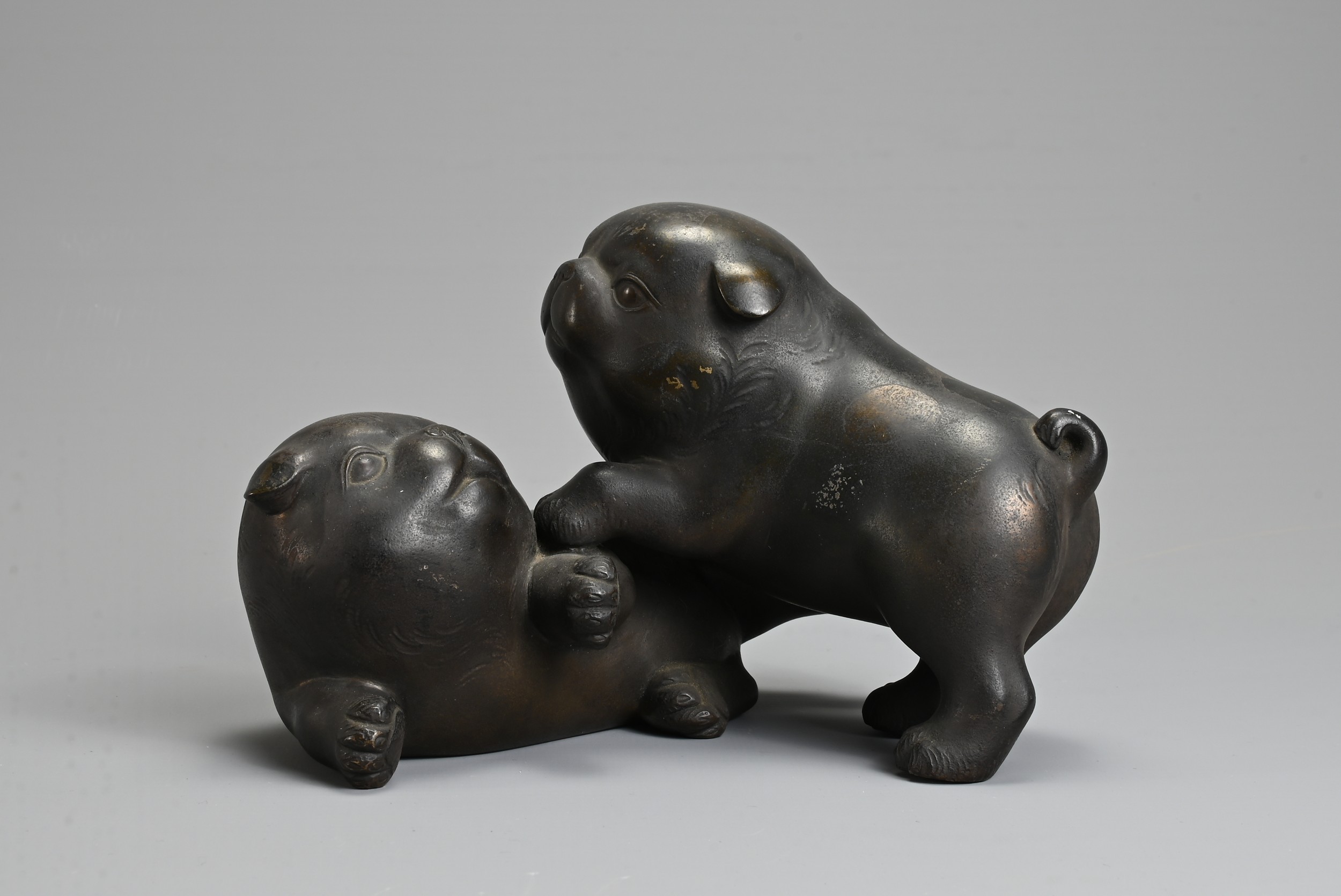 AN EARLY 20TH CENTURY JAPANESE BRONZE OF TWO PUPPIES PLAYING. Signed Tokutani with seal mark to