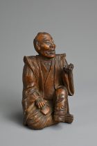 A JAPANESE MEIJI PERIOD (1868-1912) CARVED WOOD OKIMONO OF AN SEATED ELDERLY GENTLEMAN. Modelled