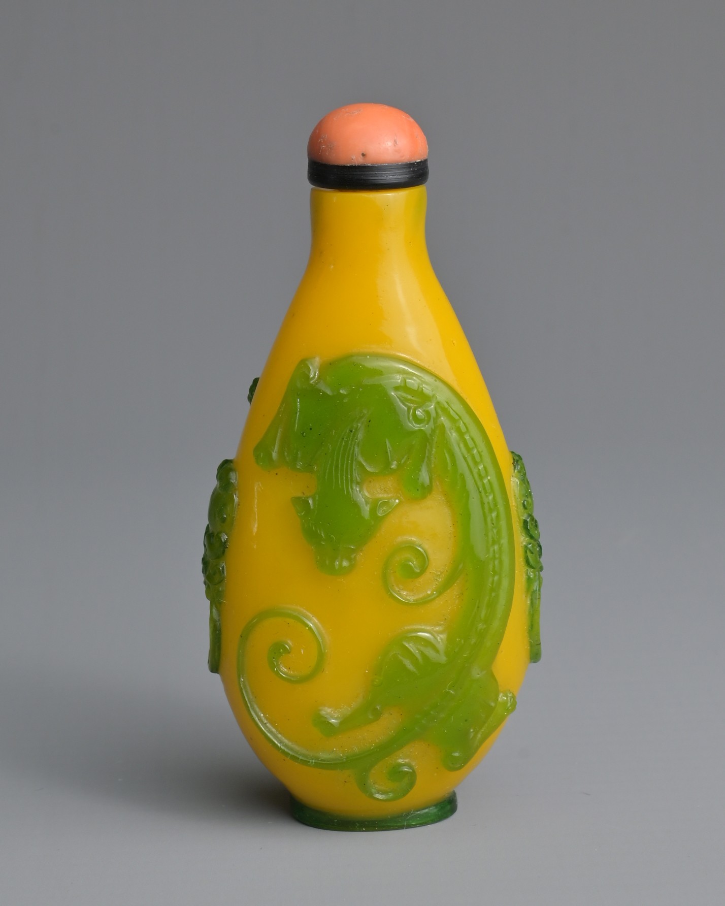 A CHINESE GREEN OVERLAY YELLOW GLASS SNUFF BOTTLE, QING DYNASTY. Of ovoid form with twin lion mask
