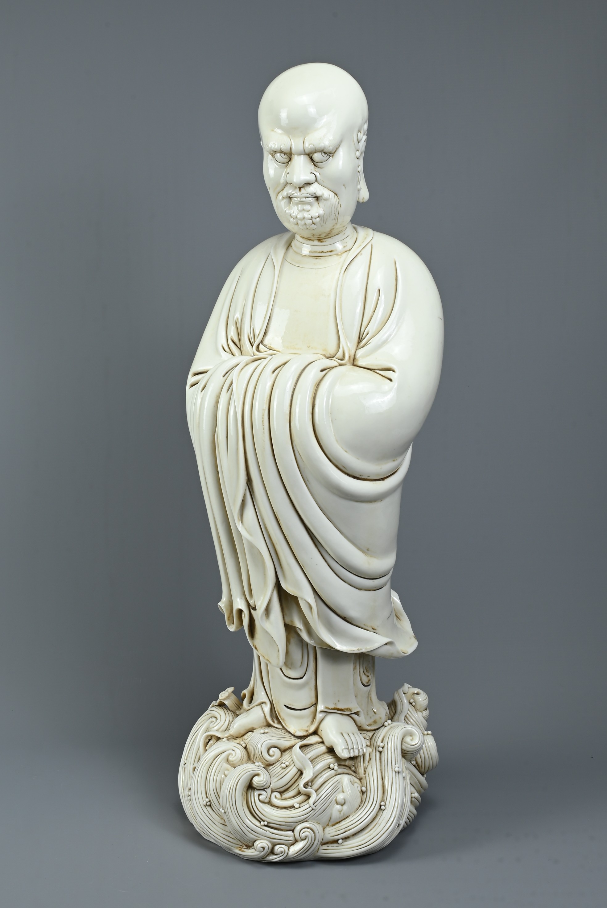 A LARGE CHINESE BLANC DE CHINE PORCELAIN FIGURE OF DAMO, 20TH CENTURY. Dressed in robes with hands