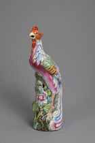 A CHINESE FAMILLE ROSE PORCELAIN MODEL OF A PHOENIX. Modelled standing on a rockwork base with peony