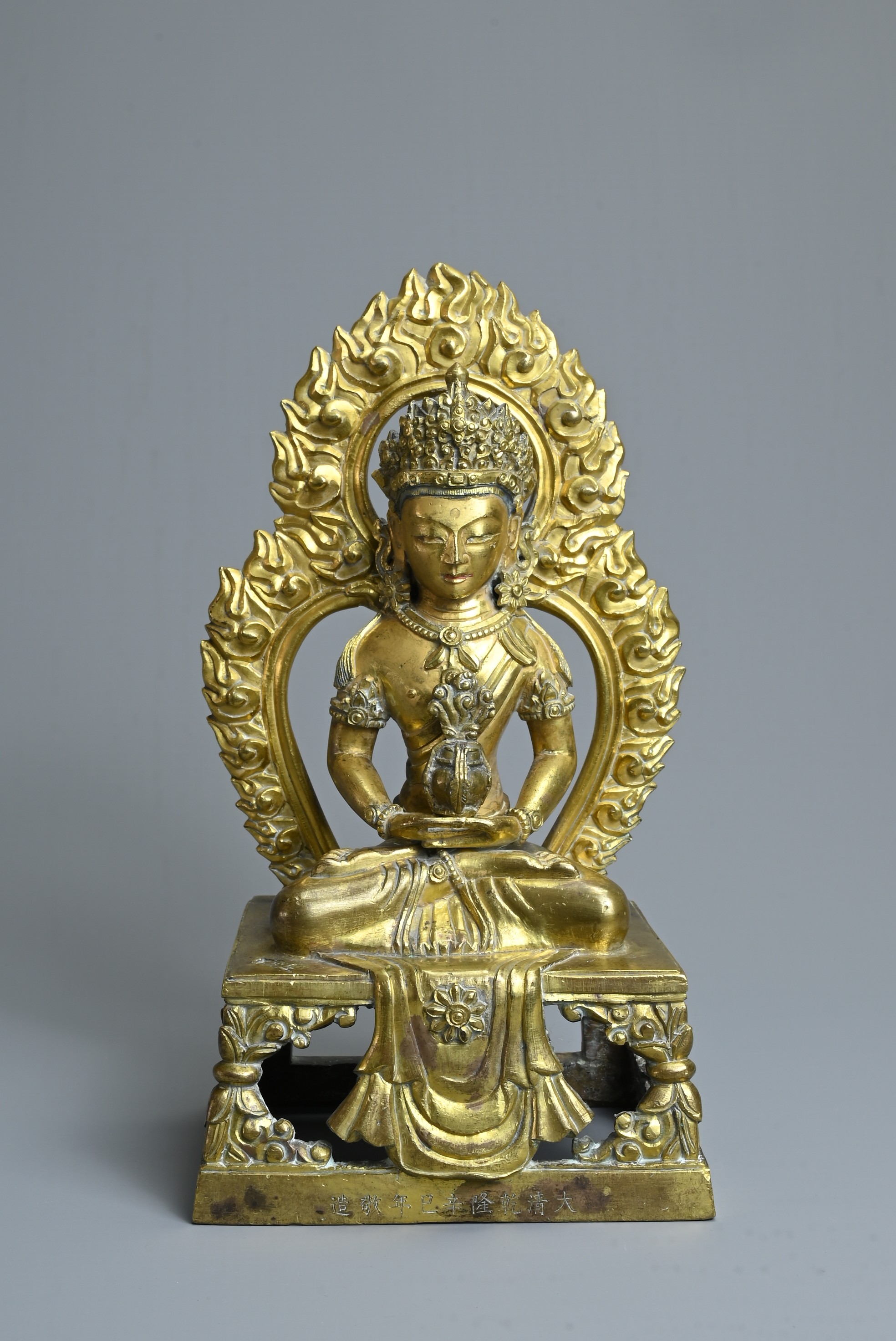 A CHINESE GILT BRONZE FIGURE OF AMITAYUS, QIANLONG PERIOD (1736-1795). The Buddha seated on an