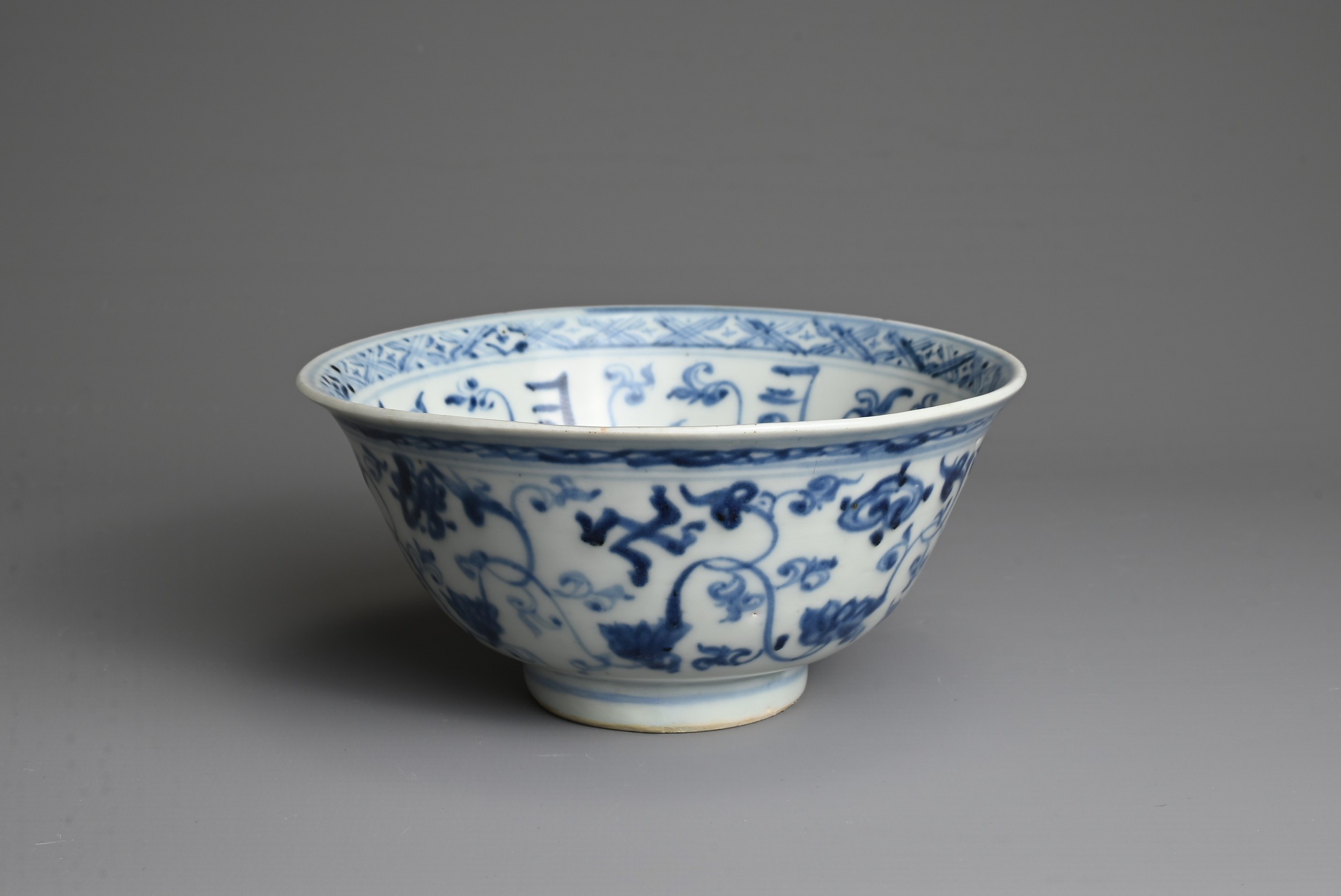 A CHINESE BLUE AND WHITE PORCELAIN BOWL, MING DYNASTY. Decorated with lotus scrolls and Buddhist