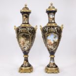 A pair of exceptionally tall ornamental vases of cobalt blue porcelain and gilt brass, decorated wit