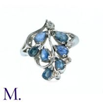 A Sapphire and Diamond Dress Ring in white gold, the six pear shape blue sapphires arranged in a