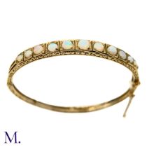 An Opal Bangle Bracelet The decoratively engraved 9ct yellow gold bangle is set with eleven good