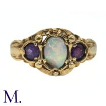 An Opal and Garnet Three Stone Ring in 9k yellow gold, the central oval shaped cabochon opal (