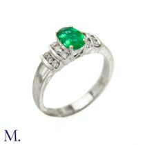 An Emerald and Diamond Ring The 18ct white gold ring is set with an oval-cut emerald of