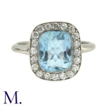 An Aquamarine And Diamond Cluster Ring in white gold, the principal cushion cut aquamarine