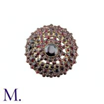 A Bohemian Garnet Brooch in yellow metal, the central round cut garnet surrounded by five rows of