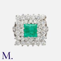 An Emerald & Diamond Cluster Ring in platinum, set with a principal step cut emerald of