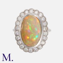 An Opal And Diamond Cluster Ring in white gold, comprising a central large oval shaped cabochon opal