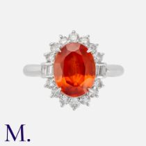 A Spessartine Garnet & Diamond Cluster Ring in platinum, set with a principal oval cut spessartine