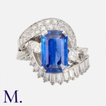 A Sapphire & Diamond Ring in 18K white gold set with an emerald-cut sapphire with round cut,