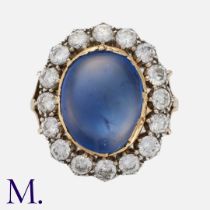 A Sapphire And Diamond Cluster Ring in yellow gold and silver, set with a principal cabochon blue