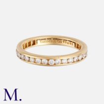 TIFFANY & CO. A Diamond Eternity Ring in 18K yellow gold, set with round brilliant diamonds weighing