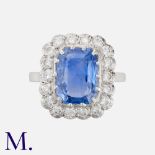 A Sapphire & Diamond Cluster Ring in 18K white gold, set with an emerald cut sapphire accompanied by