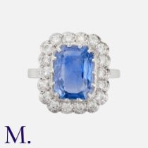 A Sapphire & Diamond Cluster Ring in 18K white gold, set with an emerald cut sapphire accompanied by