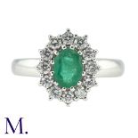 An Emerald and Diamond Cluster Ring in 18K white gold set with an oval-cut emerald (approx. 6x5mm)