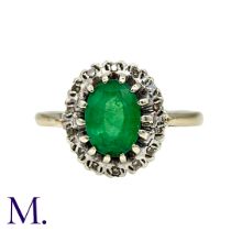 An Emerald And Diamond Cluster Ring in yellow and white gold, set with a principal oval cut